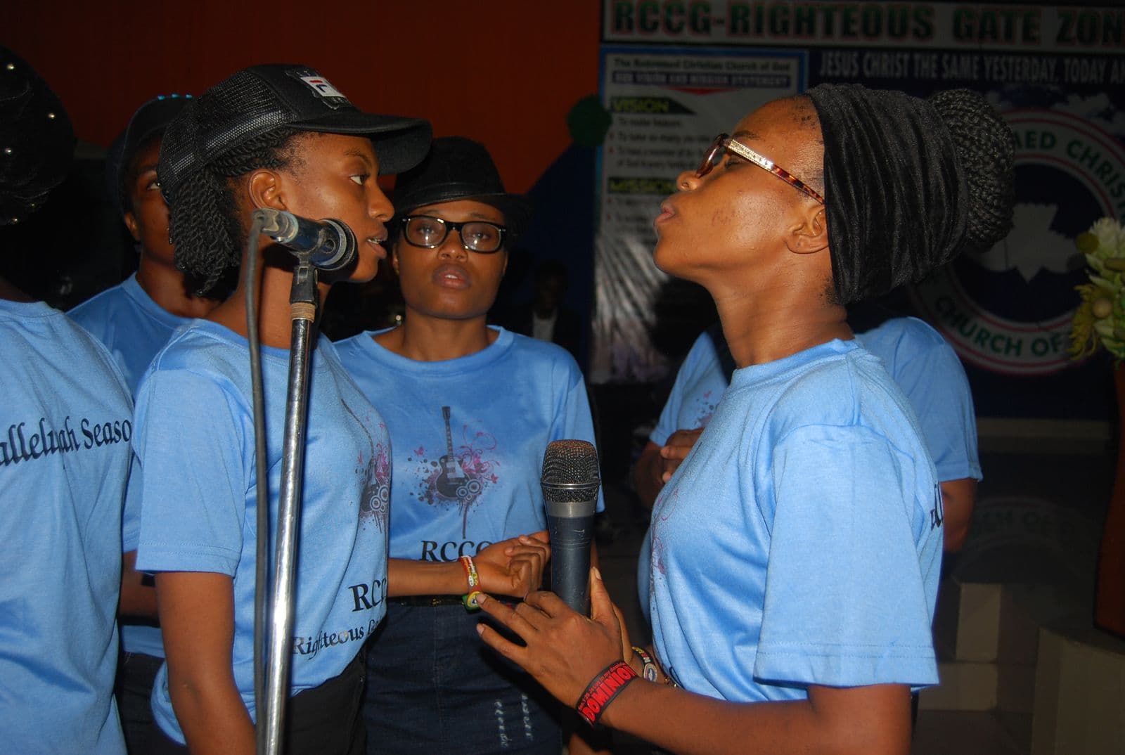 Two women singing together, one with a hand raised.