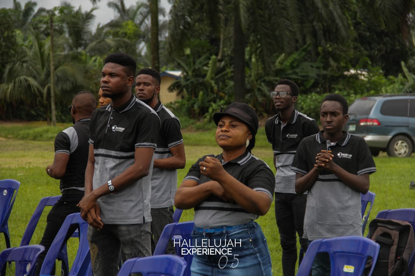 Worshippers with hands raised in the open field.