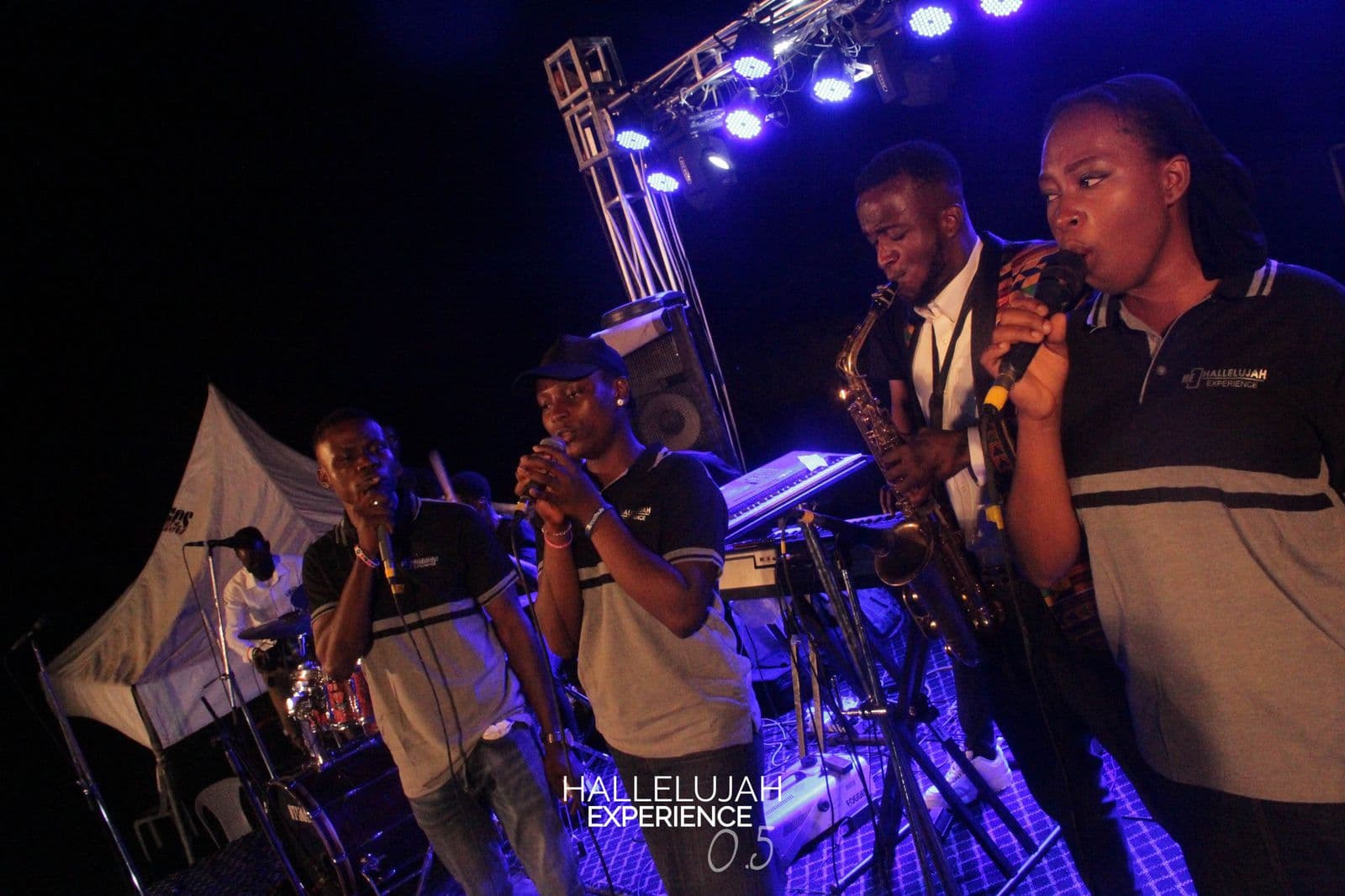 The band performing with brass instruments under blue stage light.