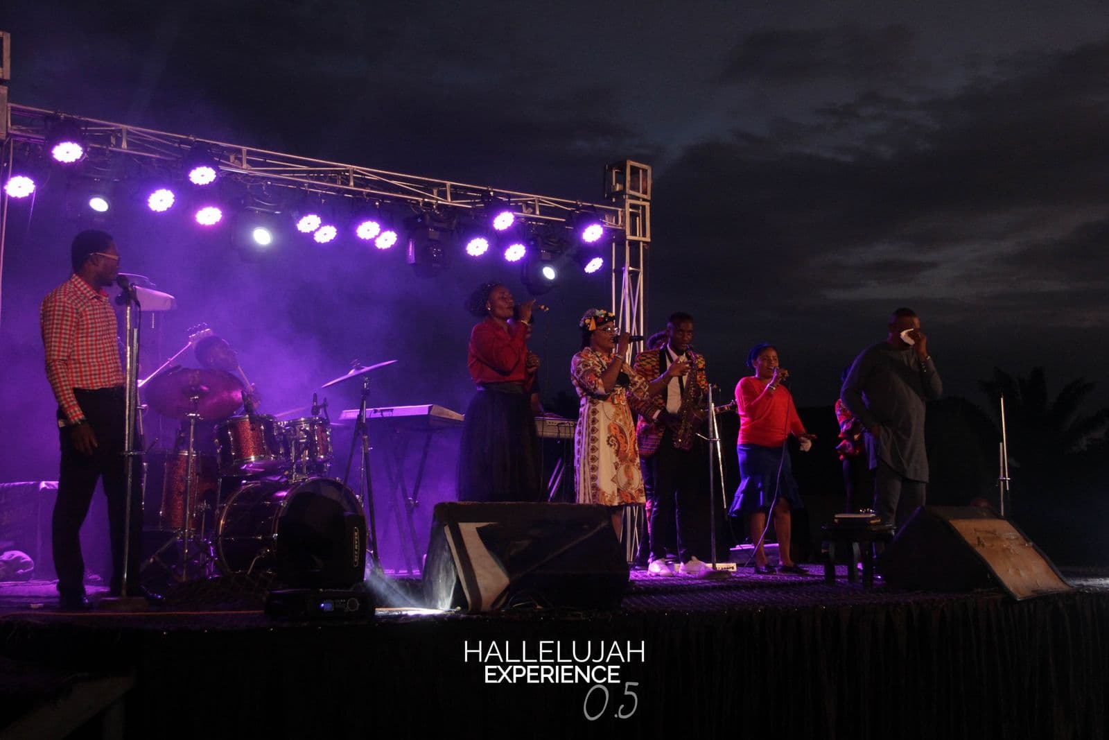The stage and full lighting rig at night, the choir gathered around the mics.