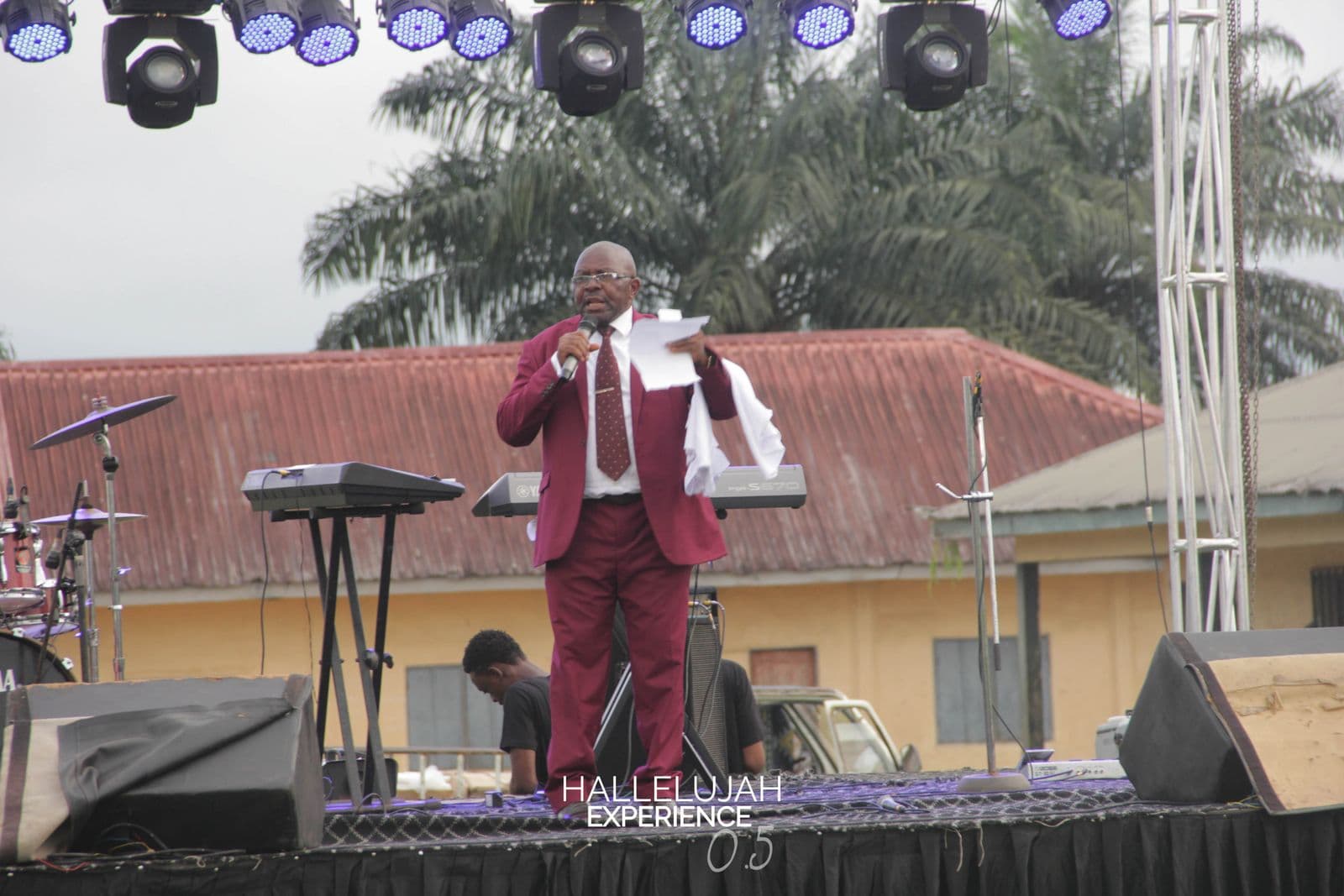 A minister addressing the crowd in daylight, the rig visible behind him.