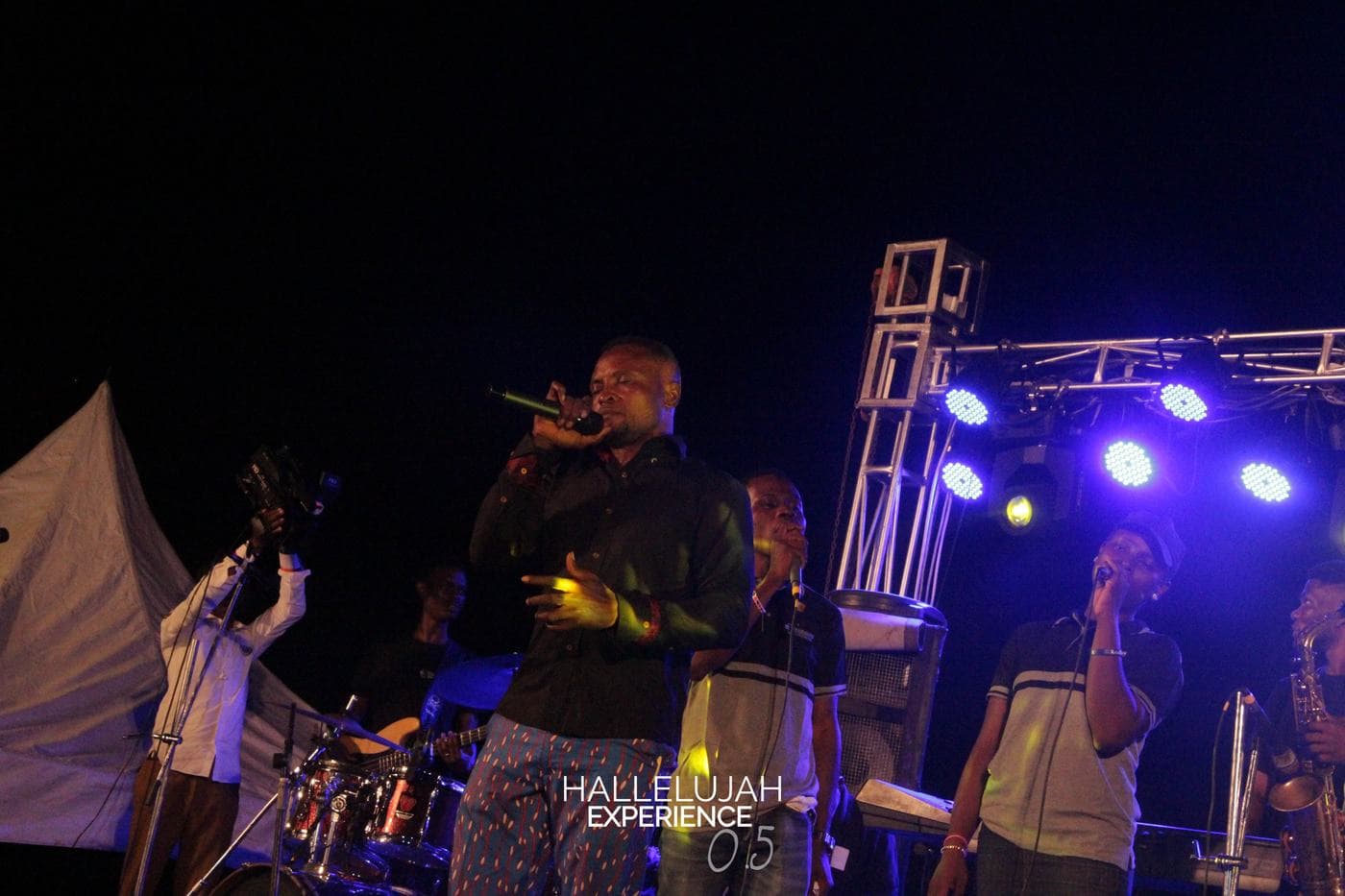 A soloist performing under stage light at night.