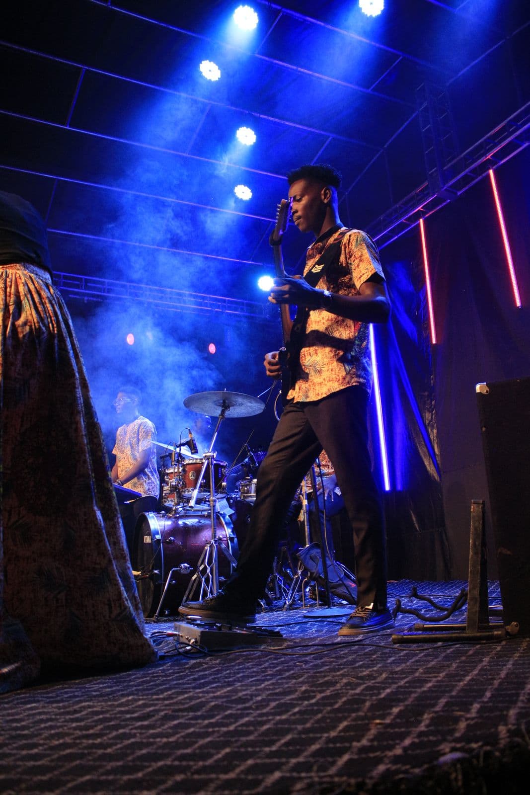 A musician silhouetted against blue and red stage light.