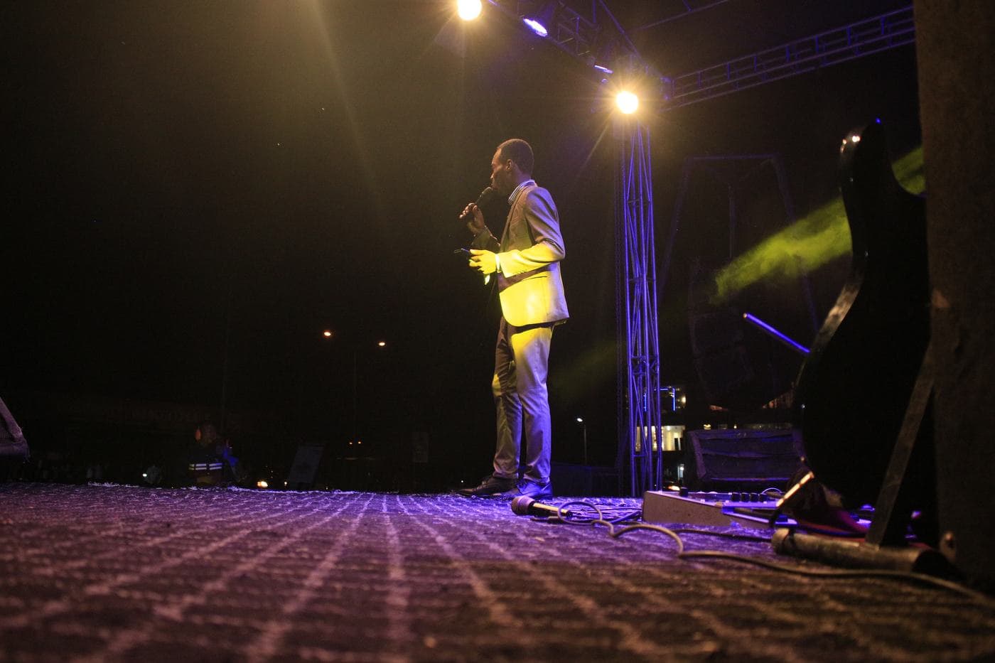 A vocalist performing under blue and purple stage light.