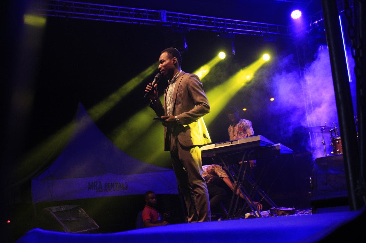 A member of the band playing under stage light.