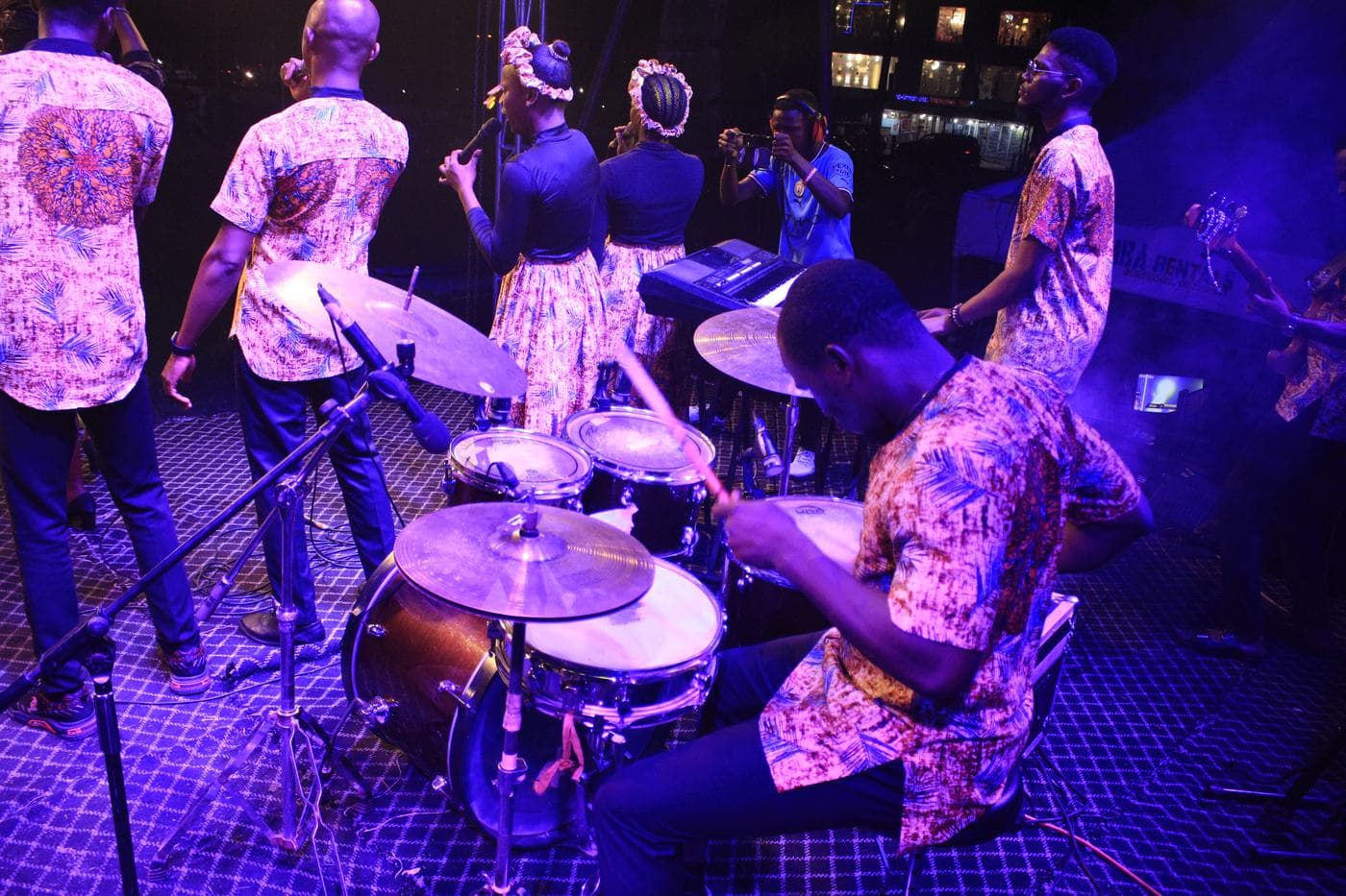 A vocalist performing under blue and purple stage light.