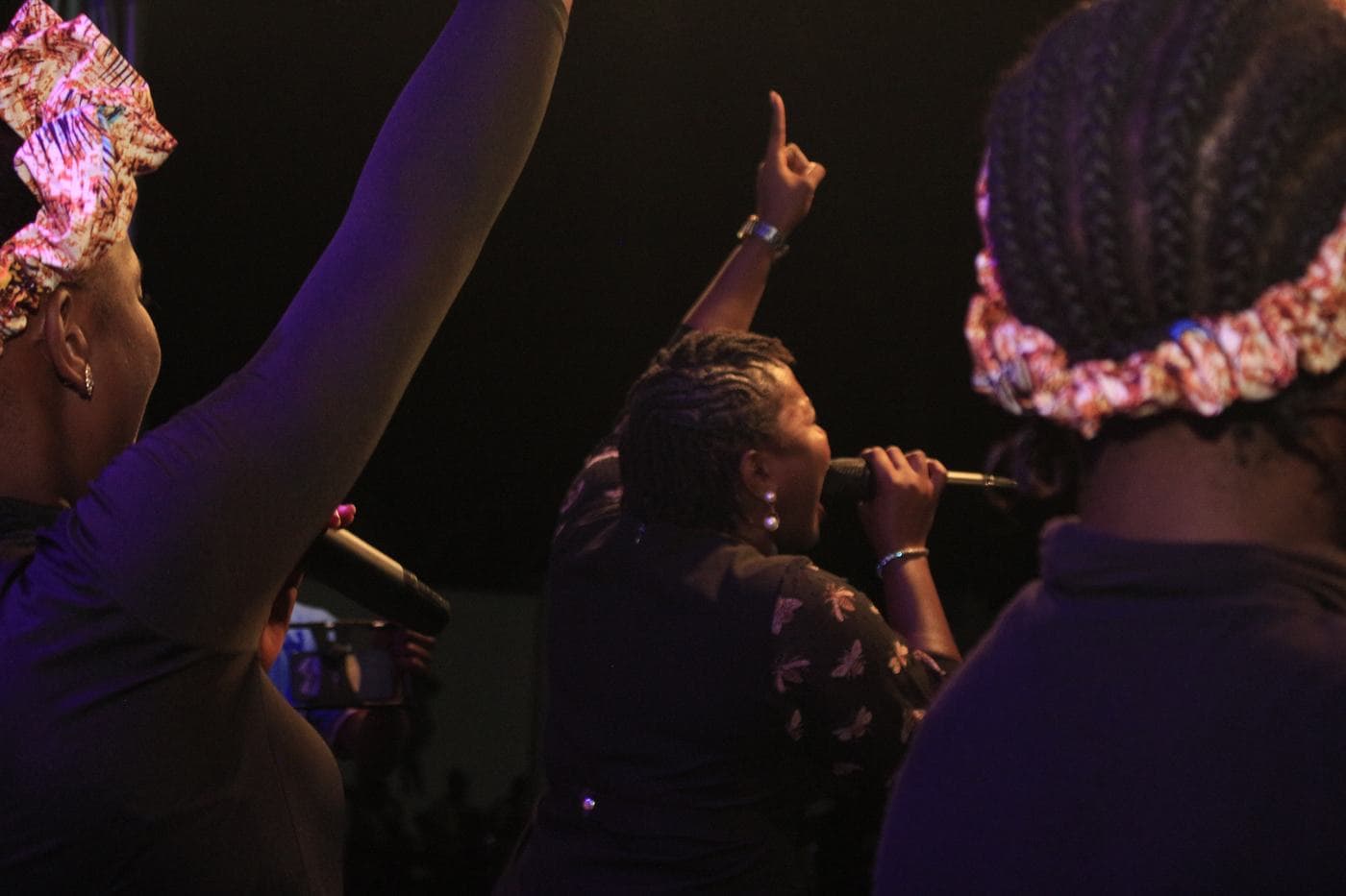 A soloist singing into a handheld microphone at night.