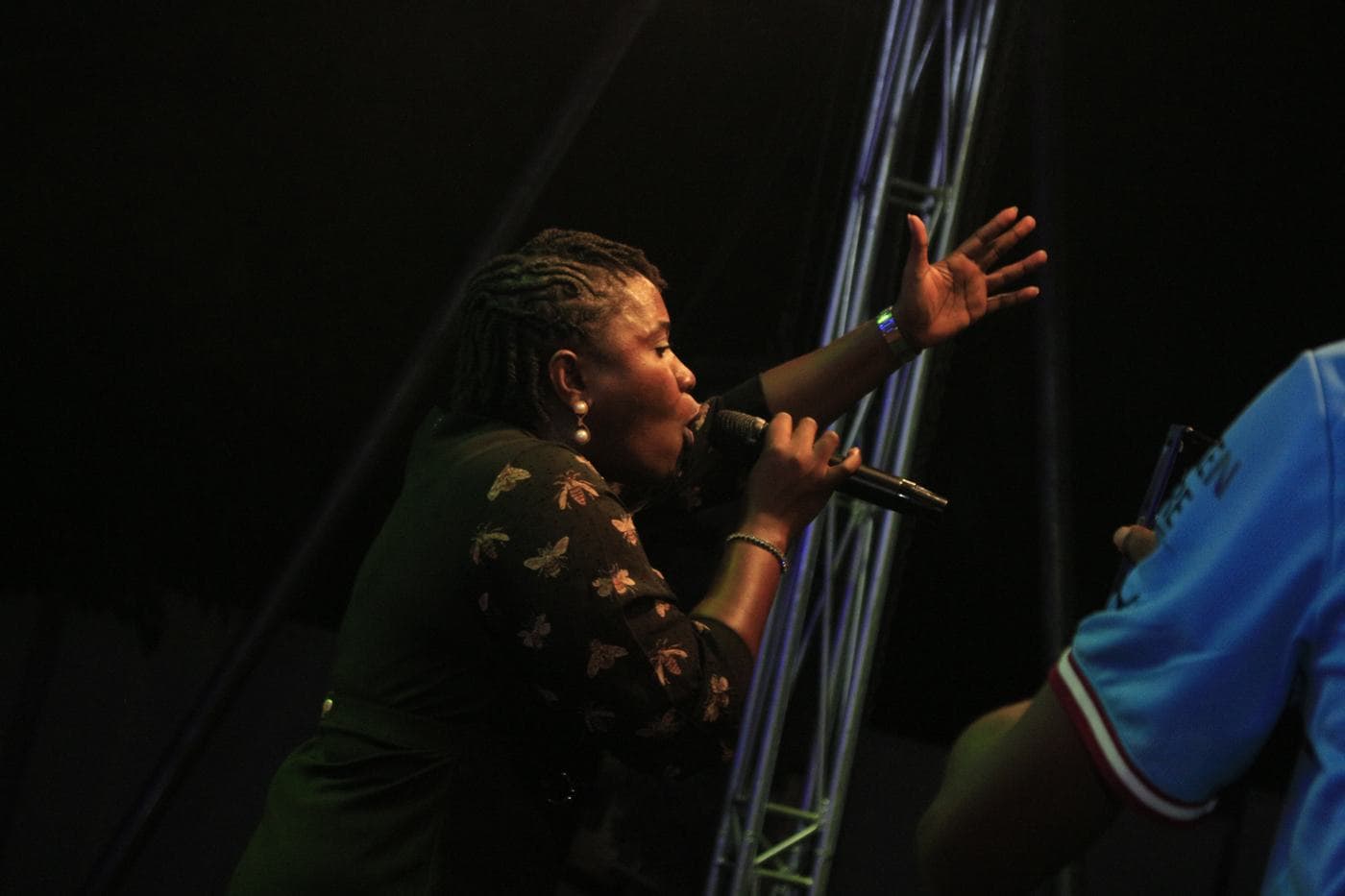 A vocalist performing under blue and purple stage light.