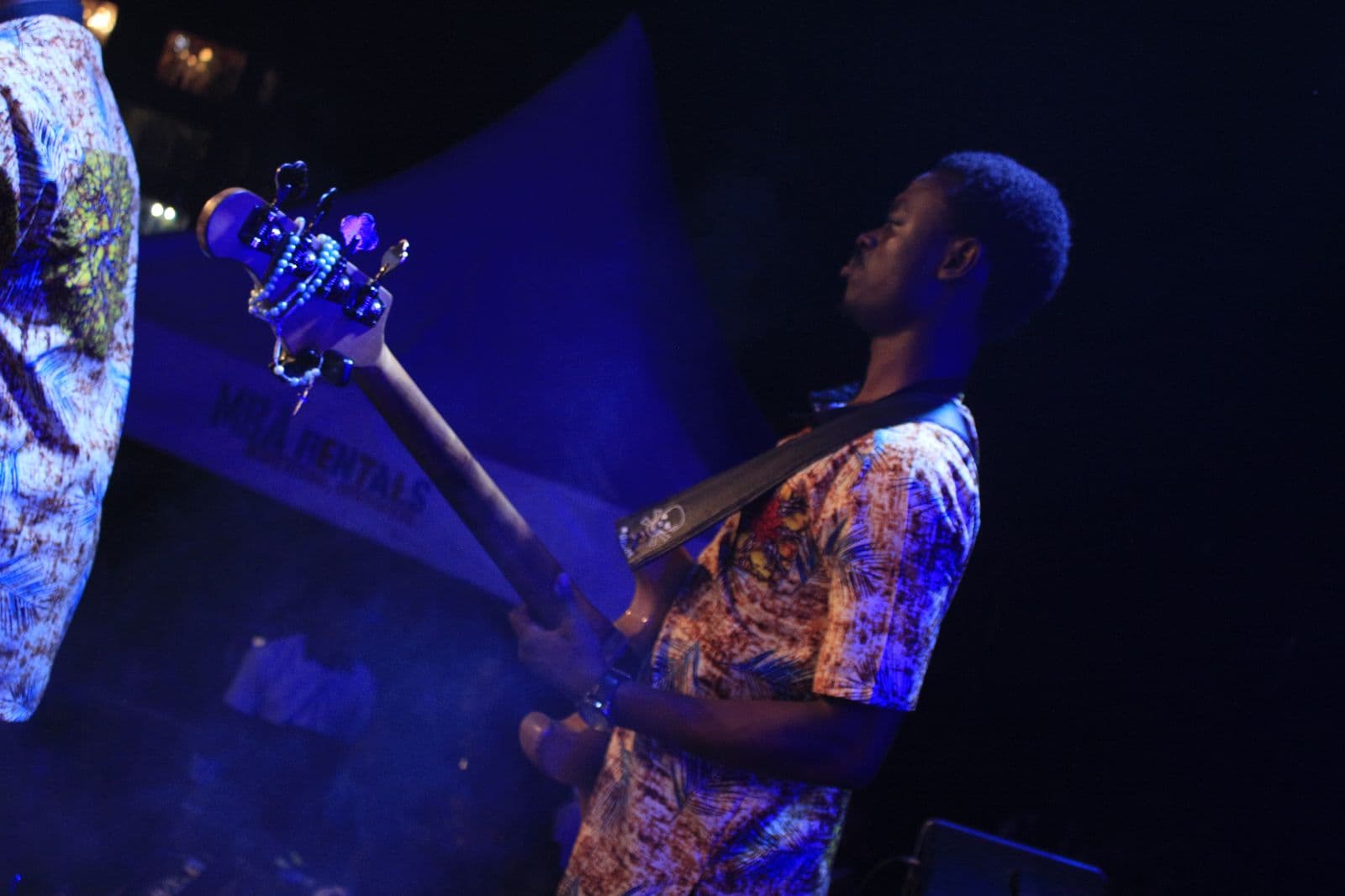 A musician playing under purple stage light.