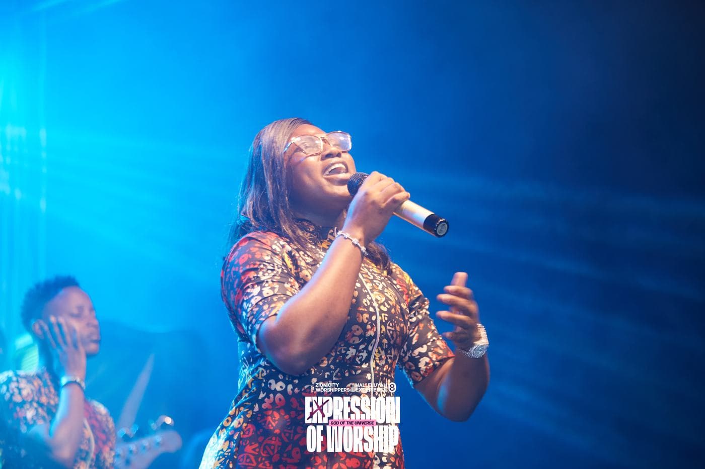 A member of the band performing under blue stage light.