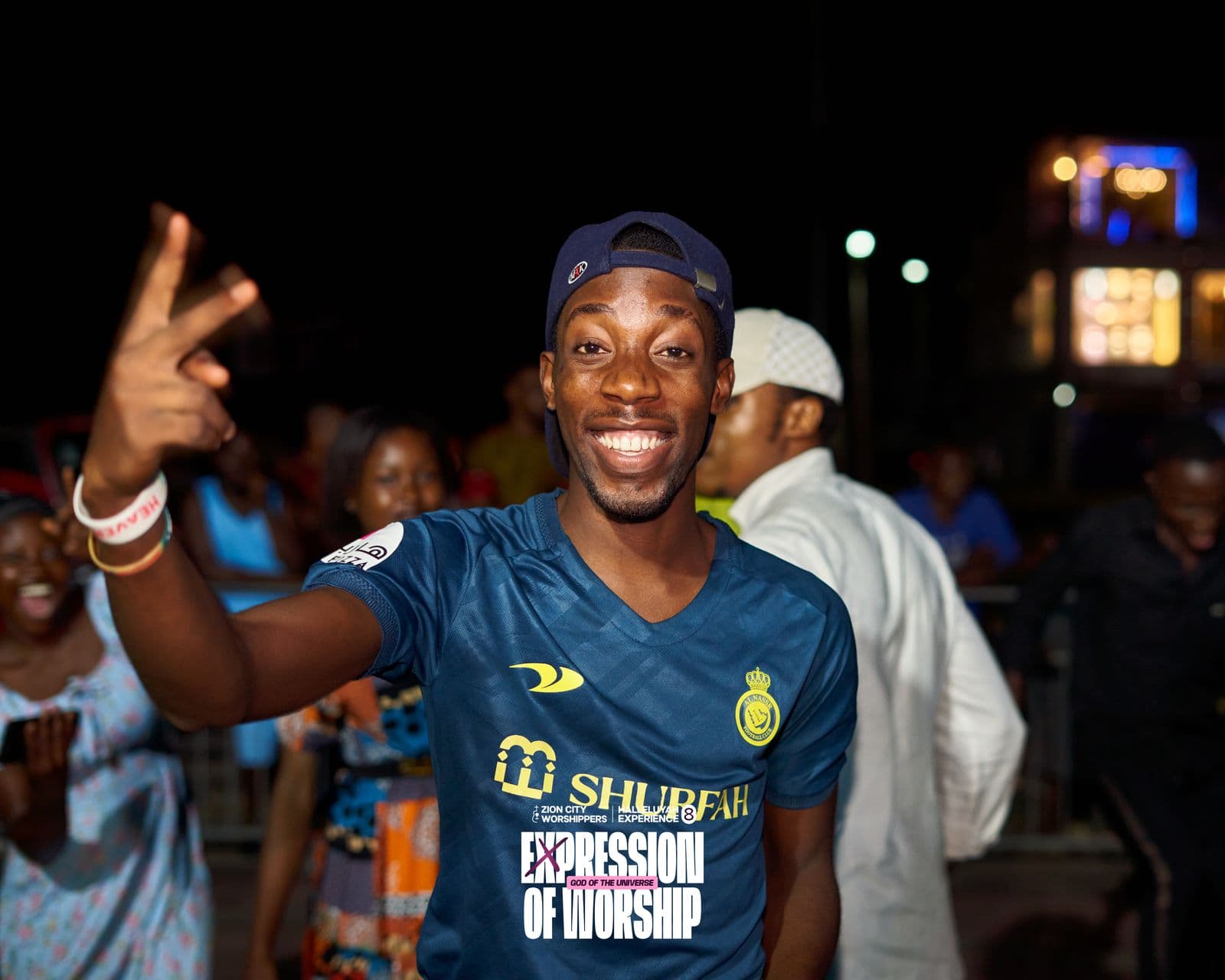 A member of the crowd cheering at night, the event branding visible.