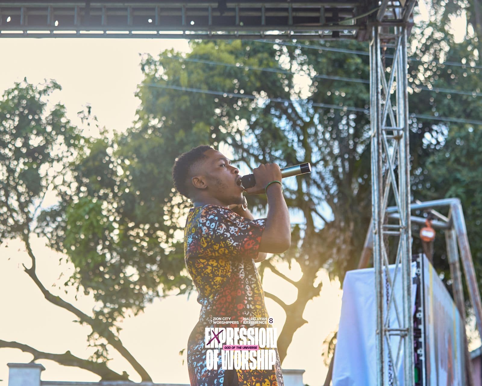 A soloist singing outdoors, backlit by the setting sun.