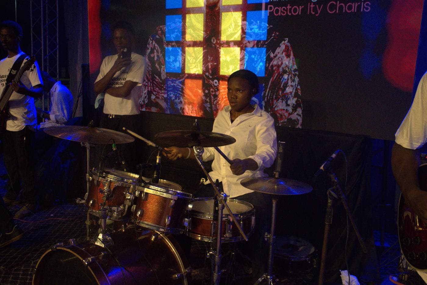 A soloist singing beneath the "Take all the Glory" backdrop.