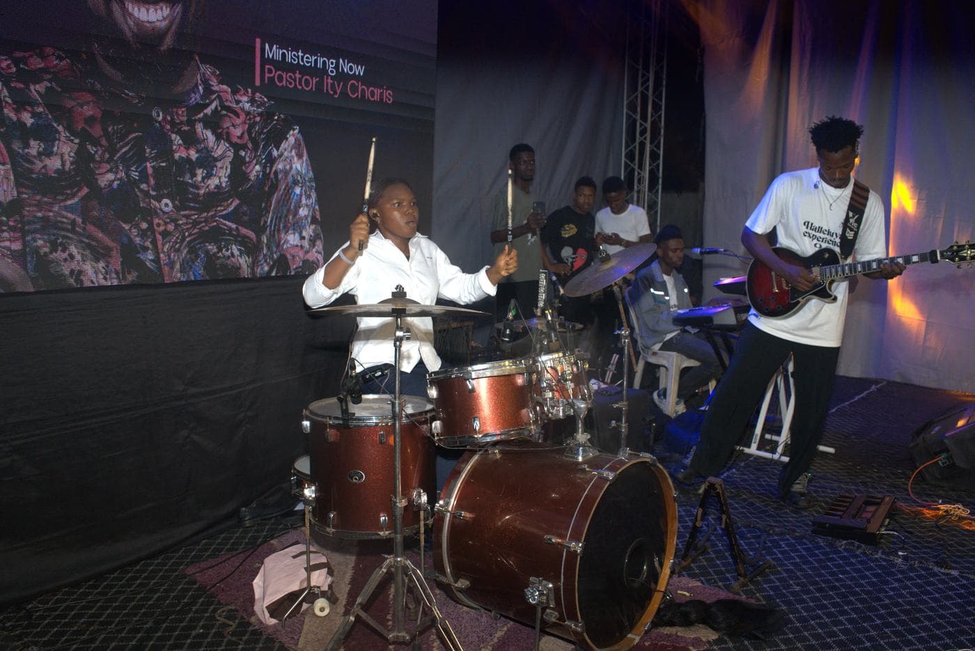 A worshipper at night, the stage lit behind.