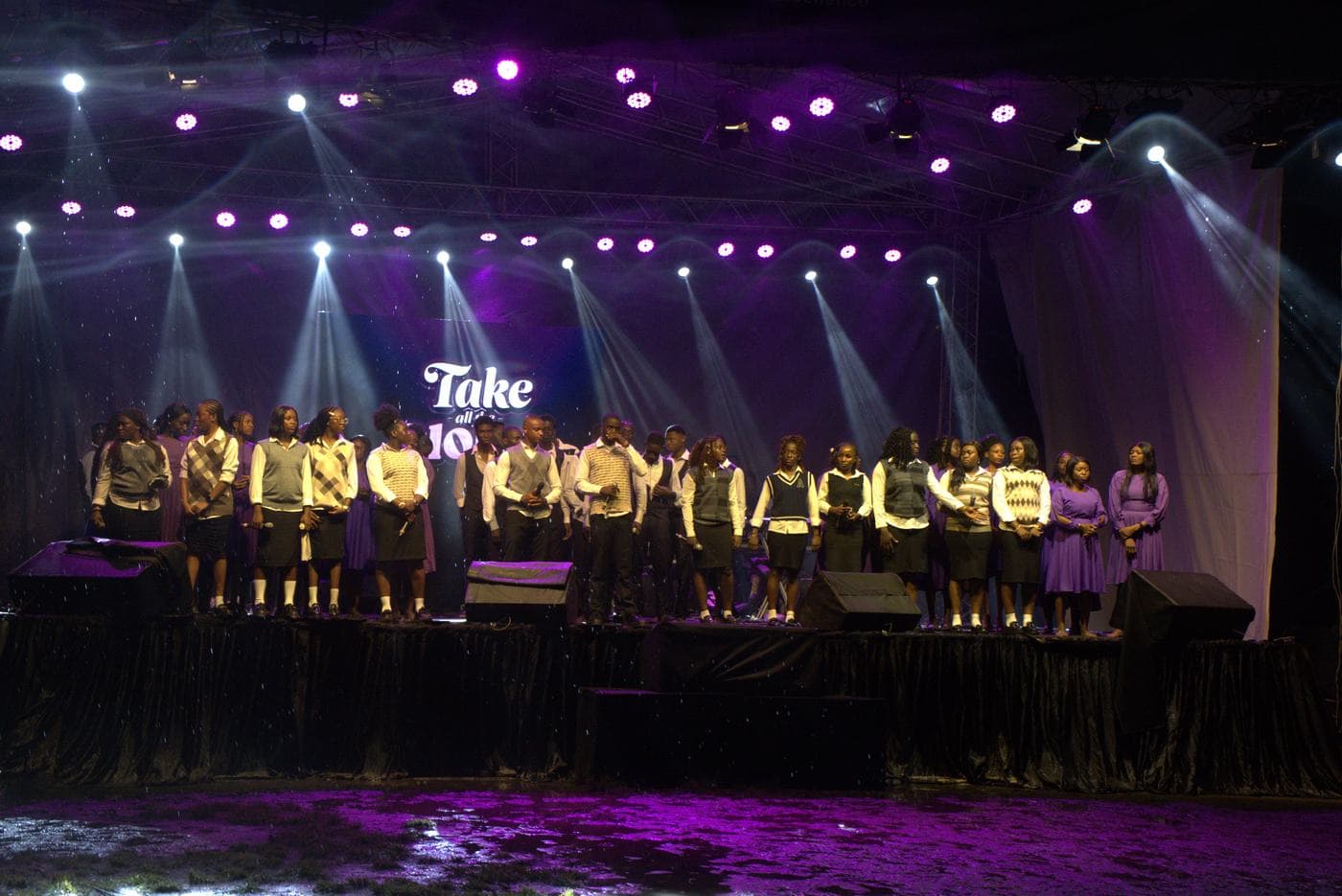 A soloist singing beneath the "Take all the Glory" backdrop.