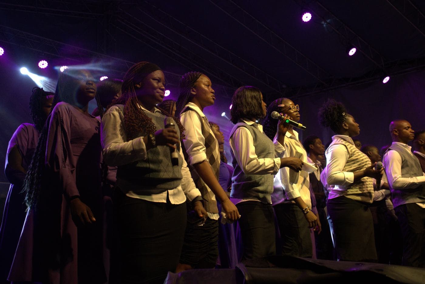 The choir performing together under purple stage light.
