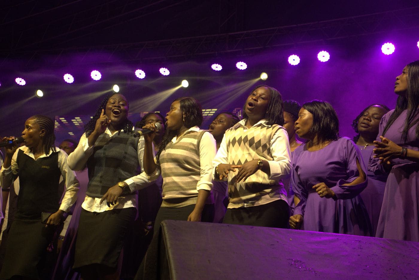A soloist singing beneath the "Take all the Glory" backdrop.