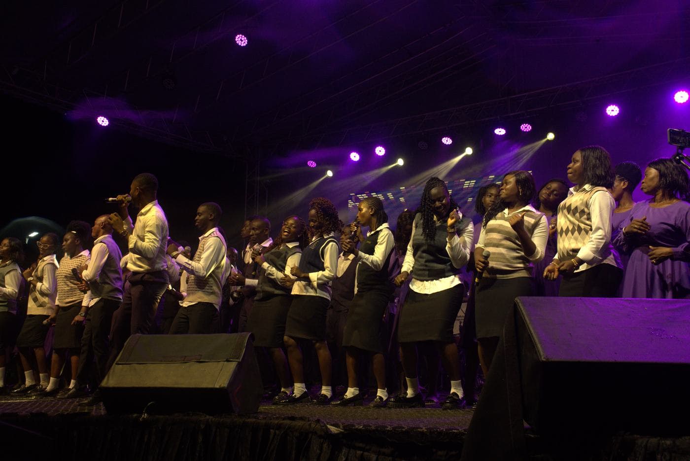 The choir performing together under purple stage light.