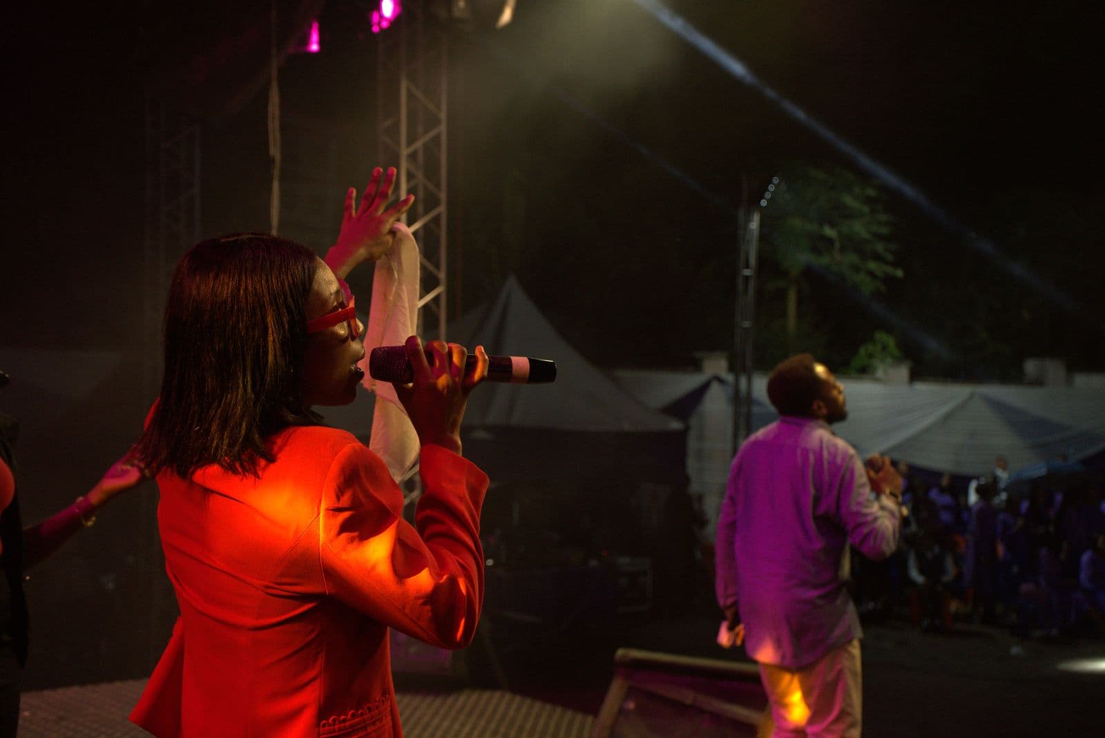 A vocalist singing under red and purple stage light.