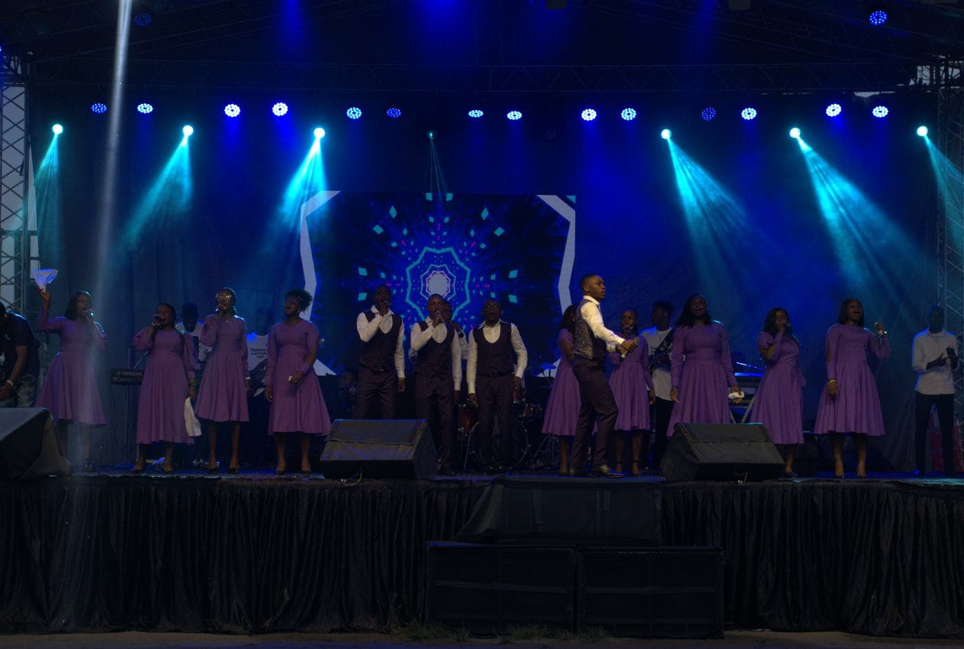 The choir performing together under purple stage light.